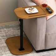 Adjustable height C-shaped end table next to sofa with snacks and remote.